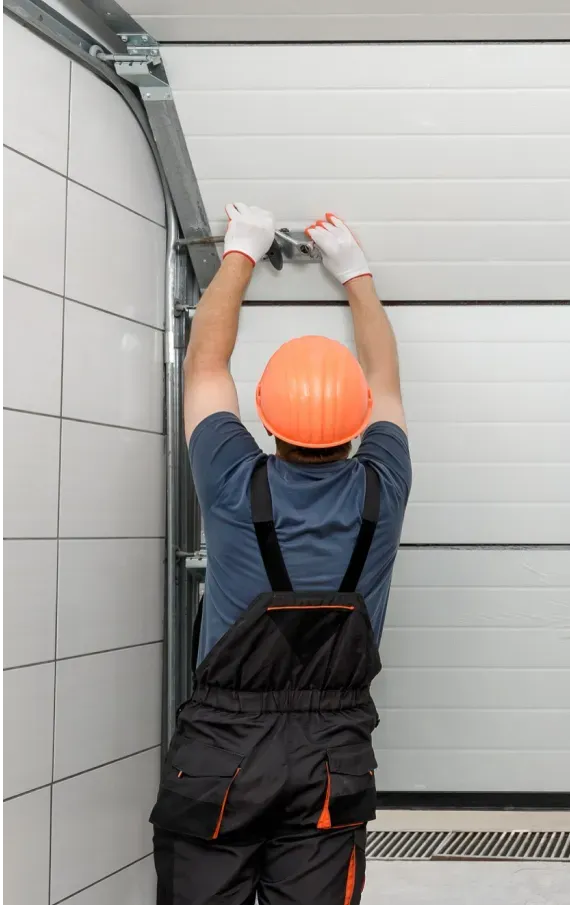 A man is installing a garage door in a garage.