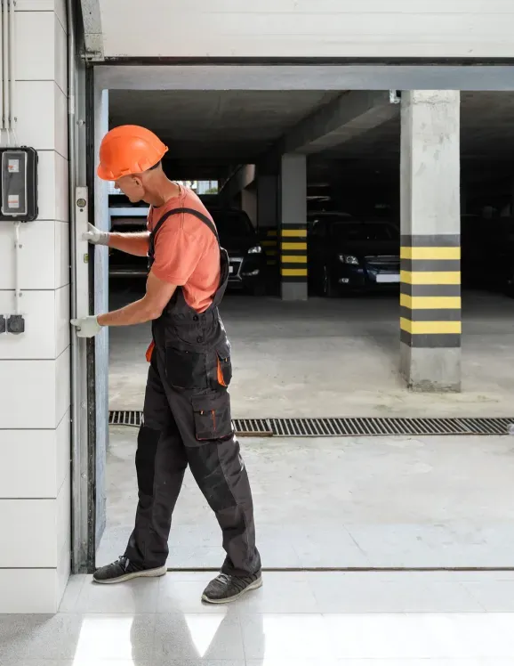 A man wearing a hard hat is opening a garage door.