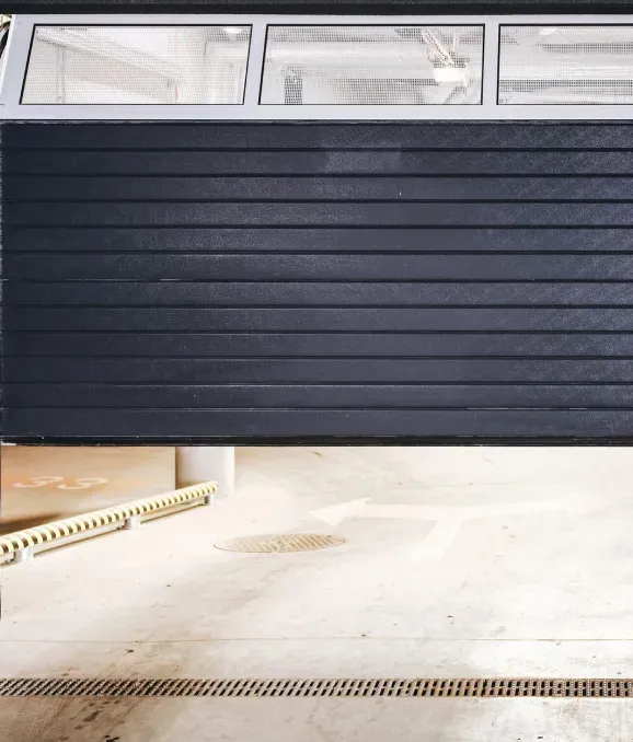 A black garage door is open in a garage.