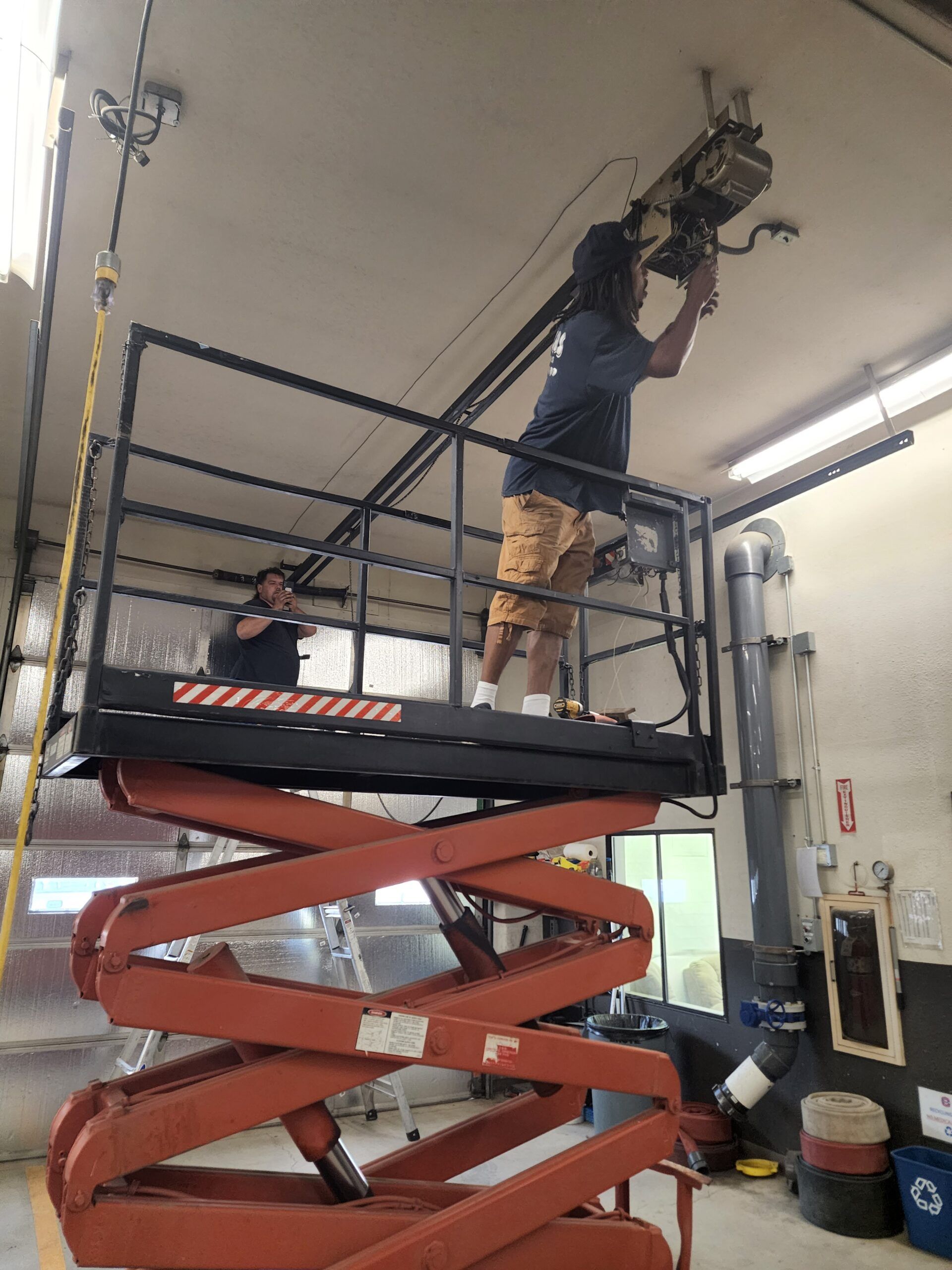 A man is working on a scissor lift in a garage.