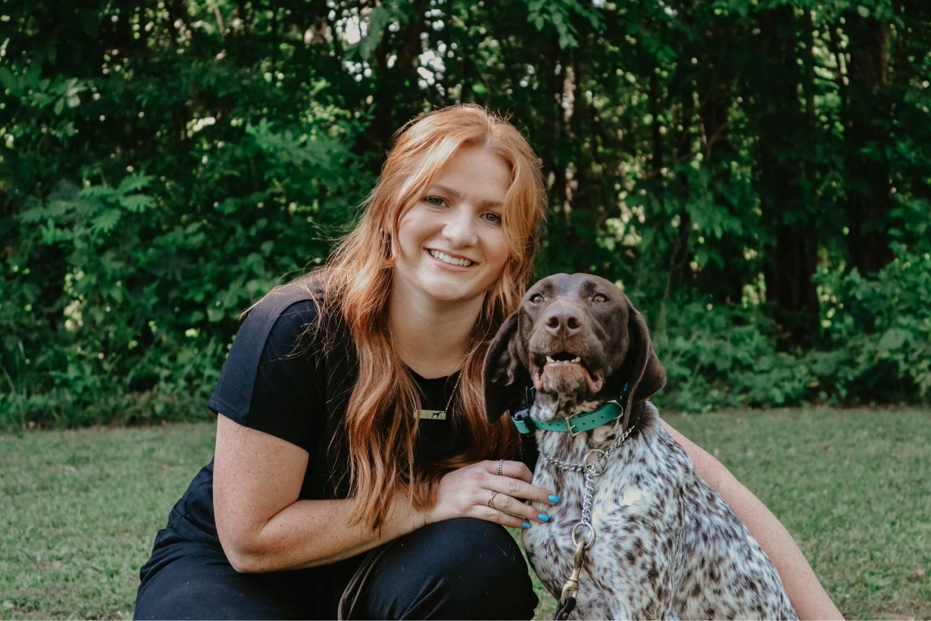 A woman is kneeling down next to a dog.