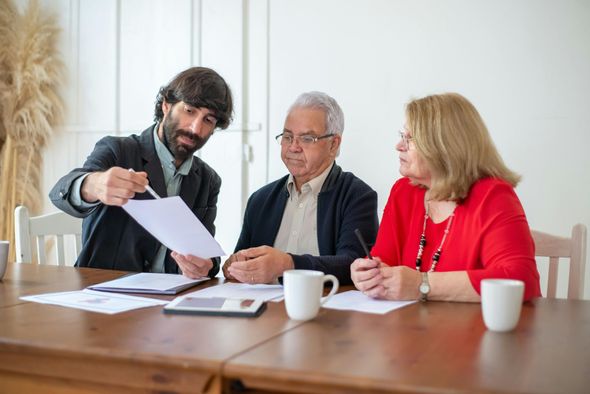 A group of people are sitting at a table looking at a piece of paper.
