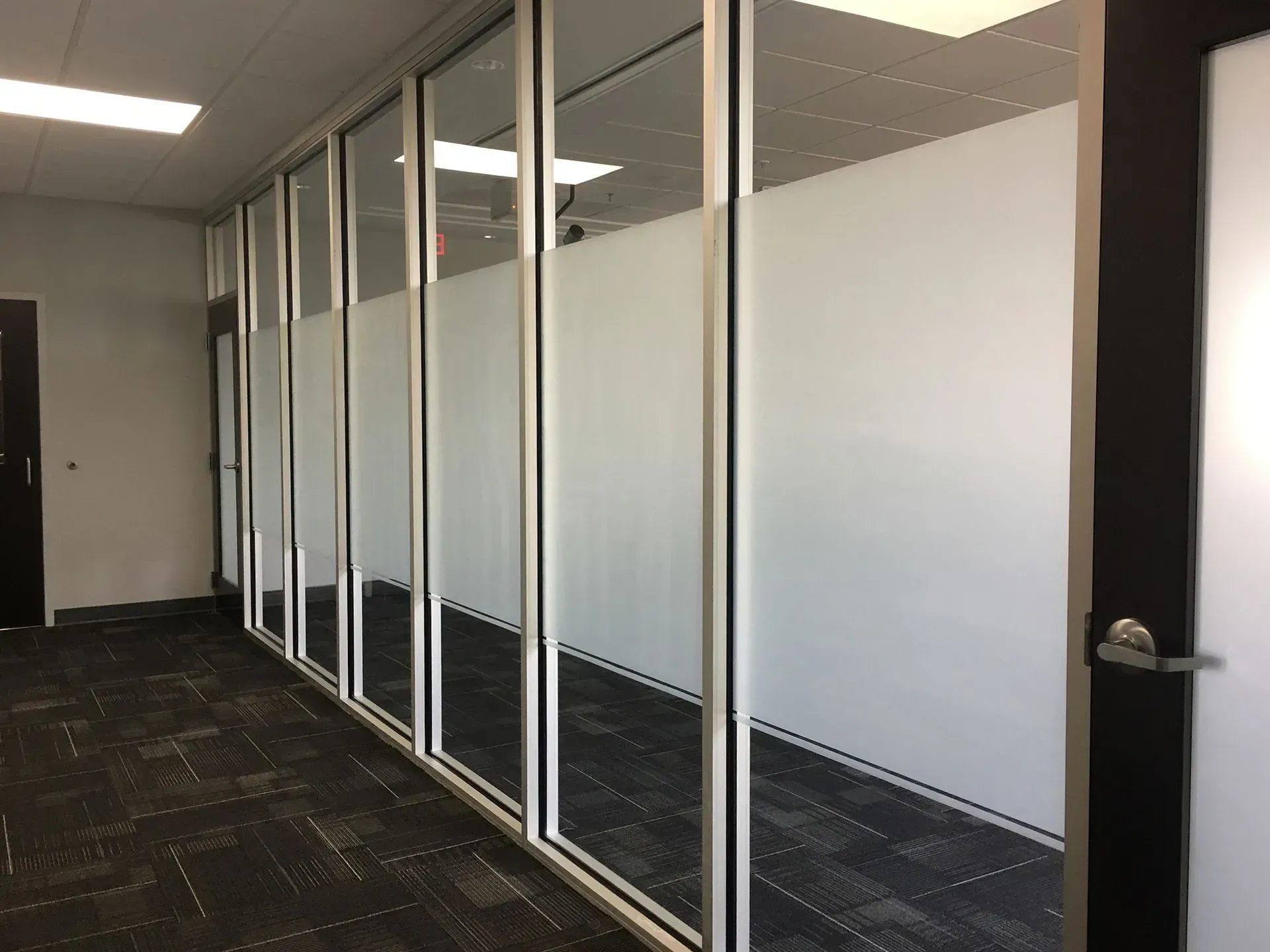 Hallway with glass-walled offices. Frosted glass provides privacy. Black trim, dark carpet.