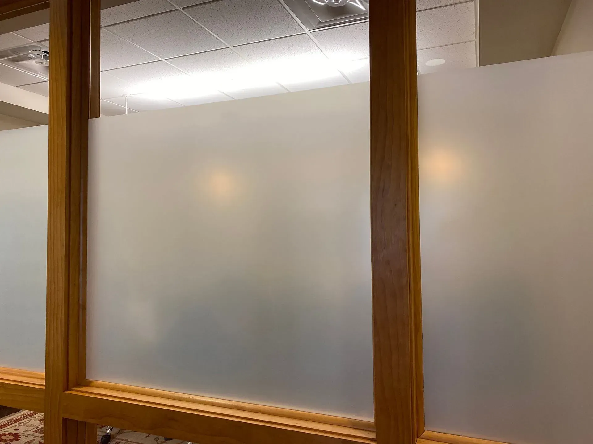 Frosted glass office partition with wooden frame.