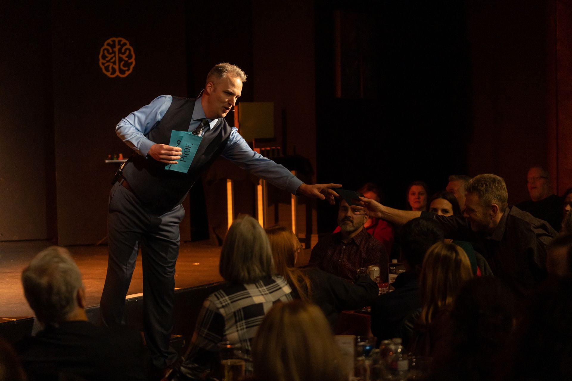 A man is standing on a stage talking to a crowd of people.