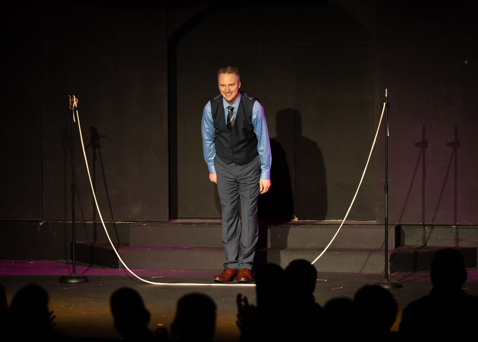 A man is standing on a stage with a rope around his waist.