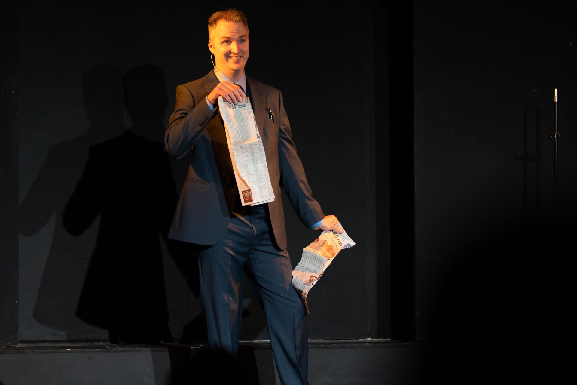 A man in a suit is standing on a stage holding a piece of paper.