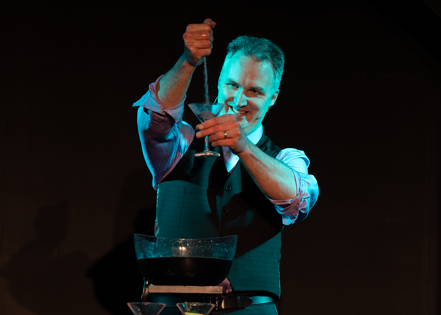 A man is pouring a drink into a martini glass.