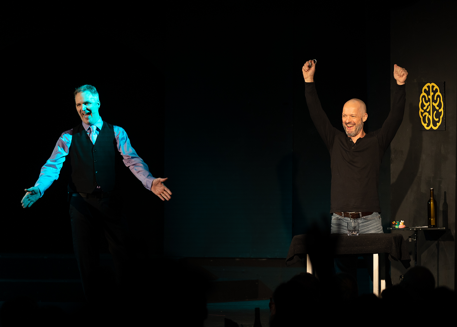 Two men are standing on a stage with their arms in the air.