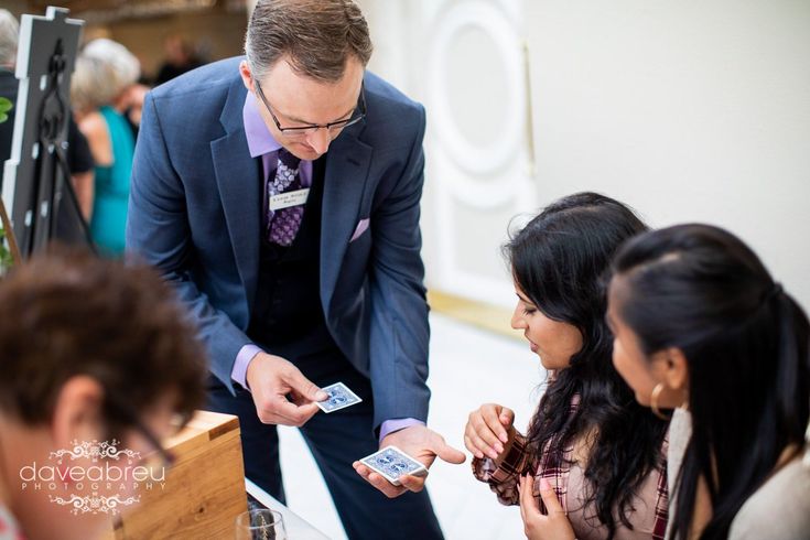 A man in a suit and tie is playing cards with a group of people.