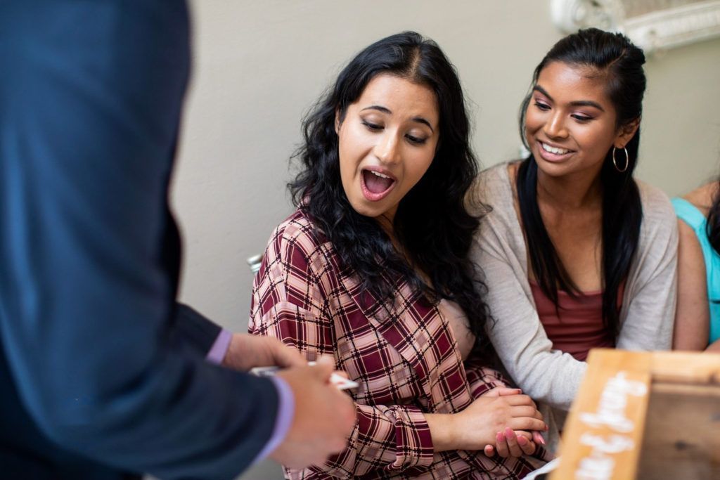 A group of young women are sitting at a table with a man.