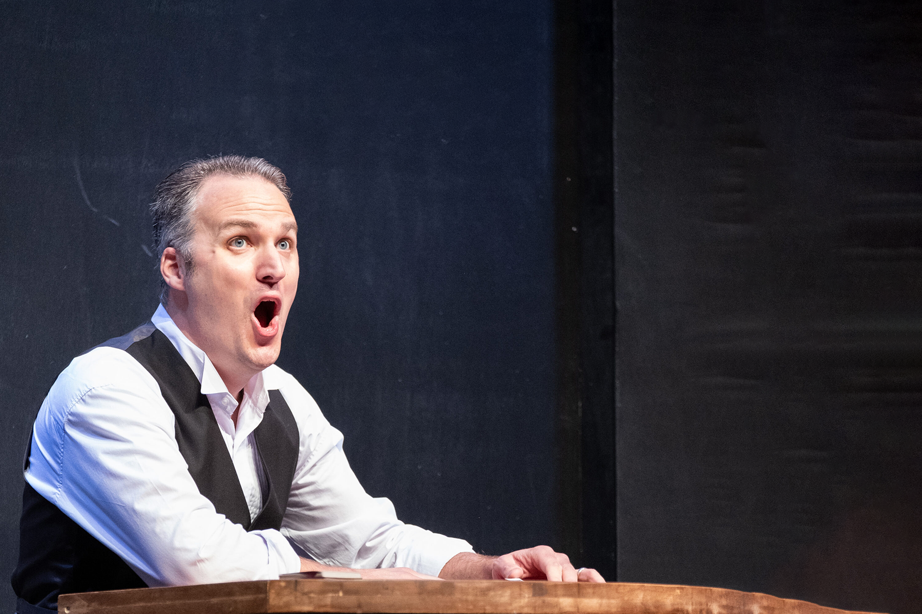 A man is sitting at a table with his mouth open.