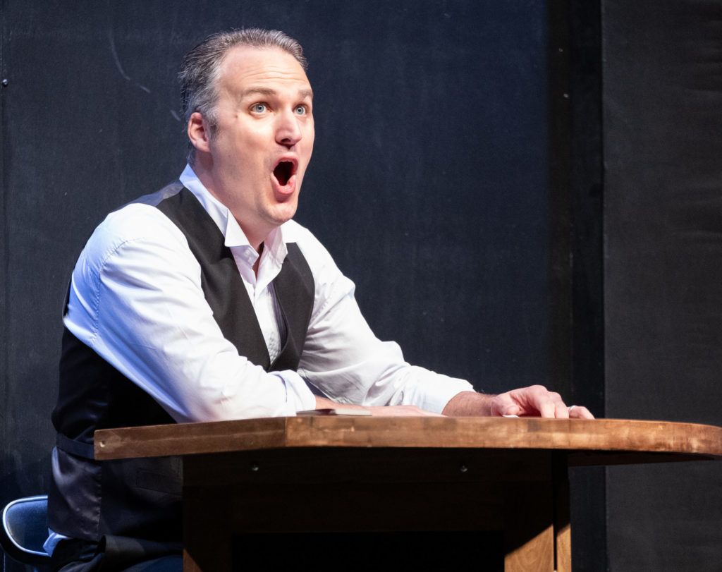 A man is sitting at a table with his mouth open