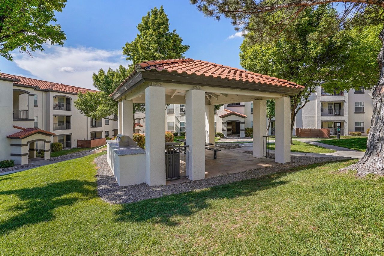 Covered pavilion with a red-tile roof in a grassy apartment complex courtyard.