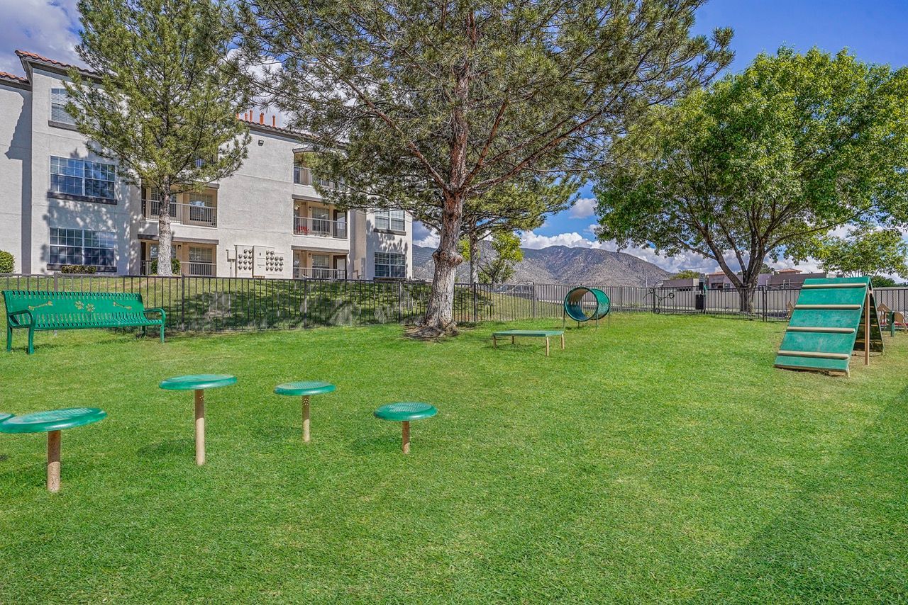 Green lawn with a playground and a multi-story apartment building in the background.