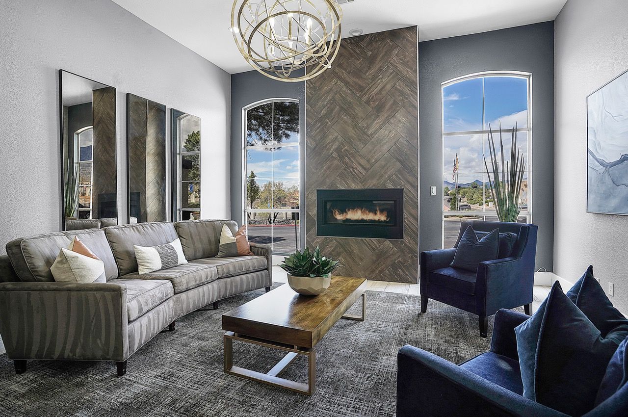 Modern apartment living room with a fireplace, tall arched windows, and contemporary seating.