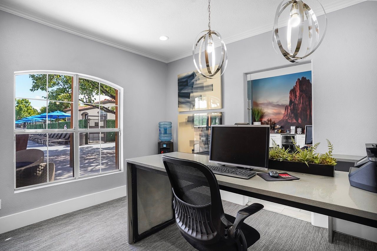 Leasing office desk with computer and a window view of the outdoor pool area.