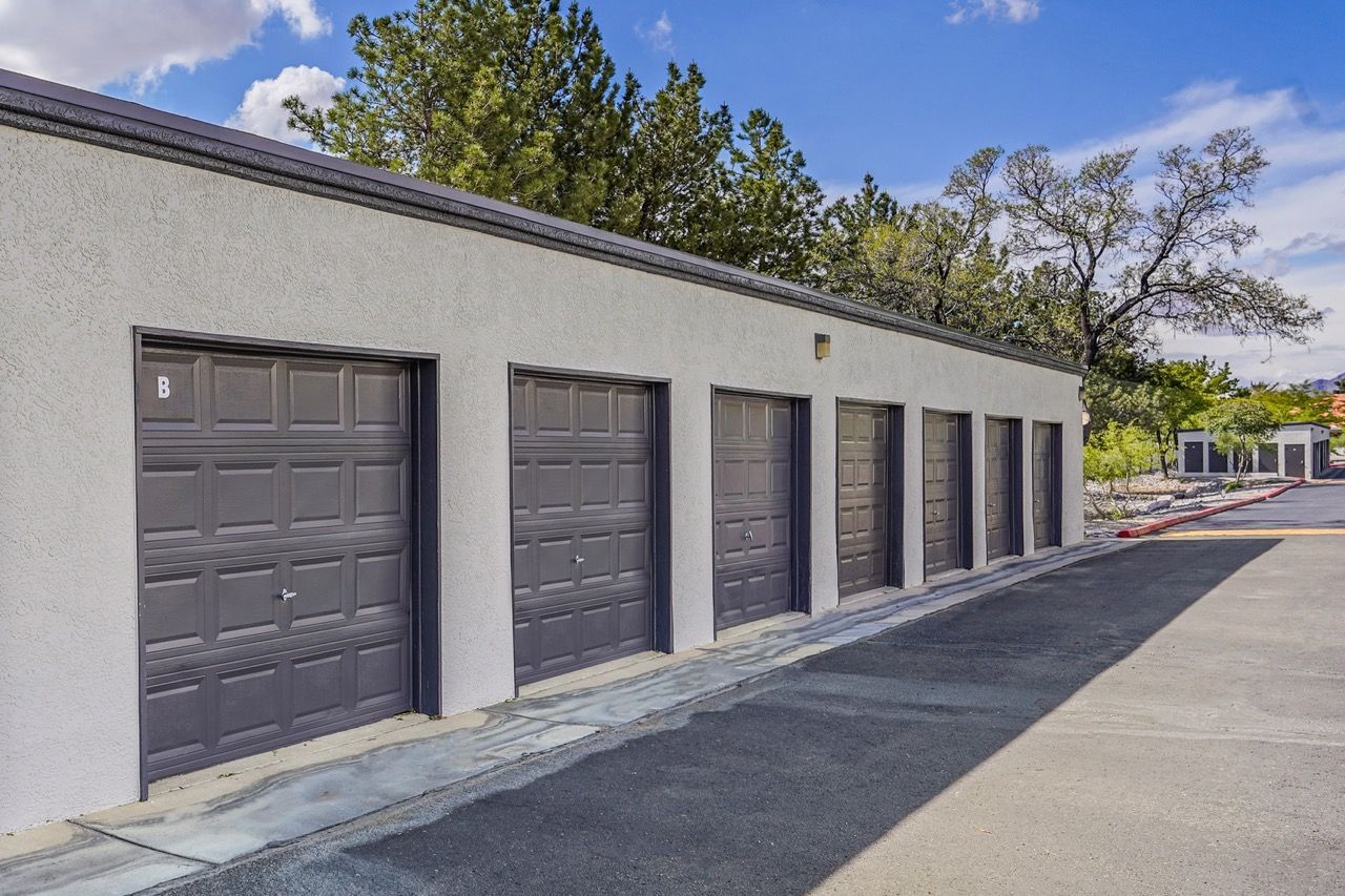 Row of brown storage garage doors along a stucco building exterior.