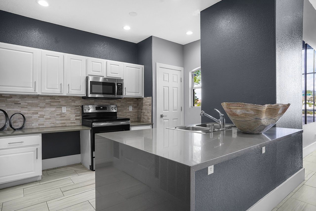 Modern apartment kitchen with white cabinets, stainless steel appliances, and a large island.