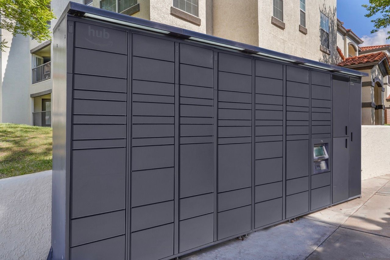 Row of gray parcel lockers outside an apartment building.