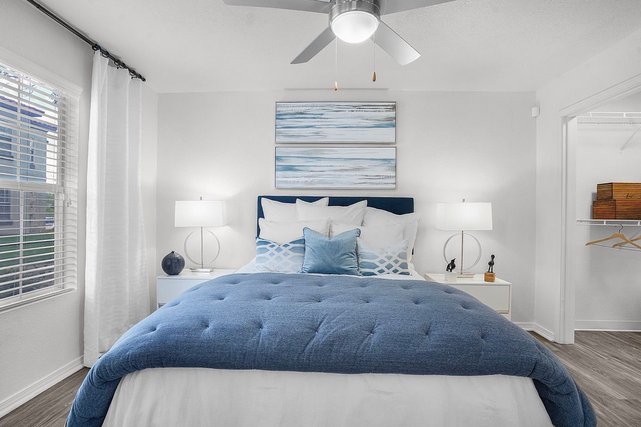 Bright bedroom with a blue tufted bed, white bedding, and open closet.