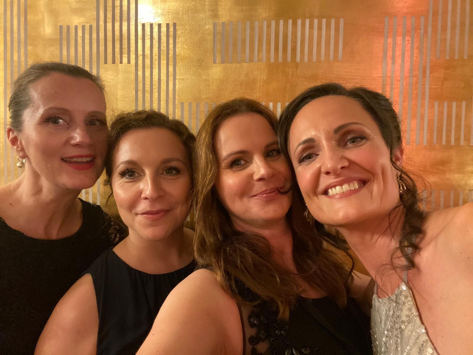 Vier Frauen posieren für ein Foto vor einer goldenen Wand