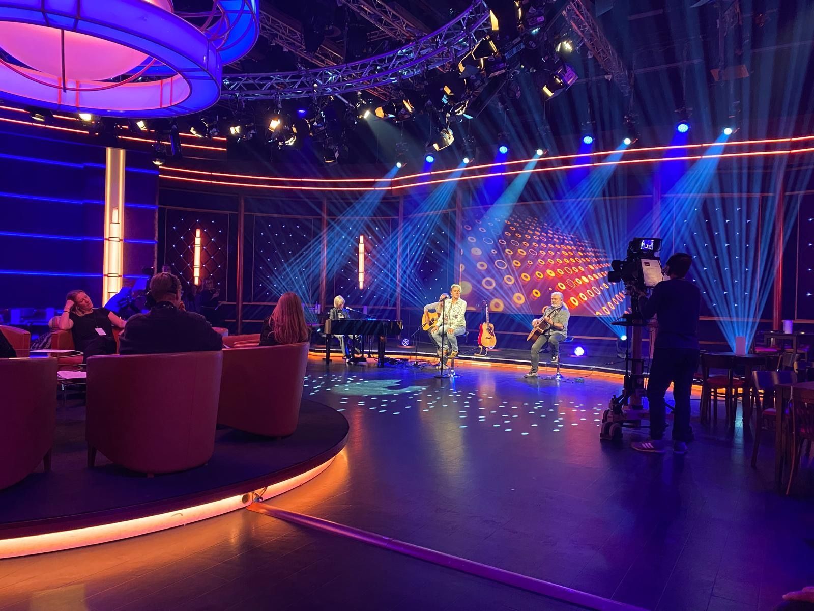 Eine Gruppe von Menschen tritt auf einer Bühne in einem dunklen Raum auf