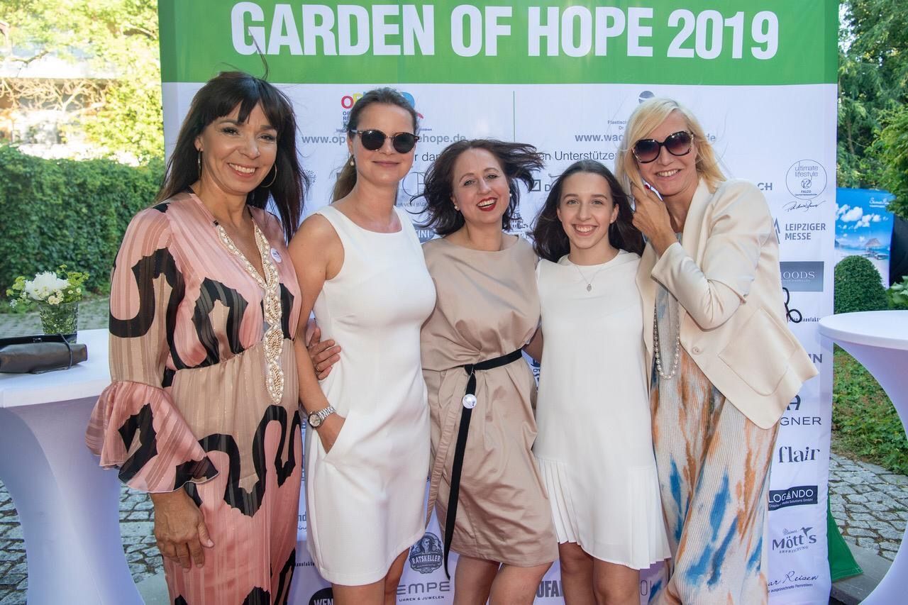 Eine Gruppe von Frauen posiert für ein Foto vor einem Schild mit der Aufschrift „Garten der Hoffnung 2019“
