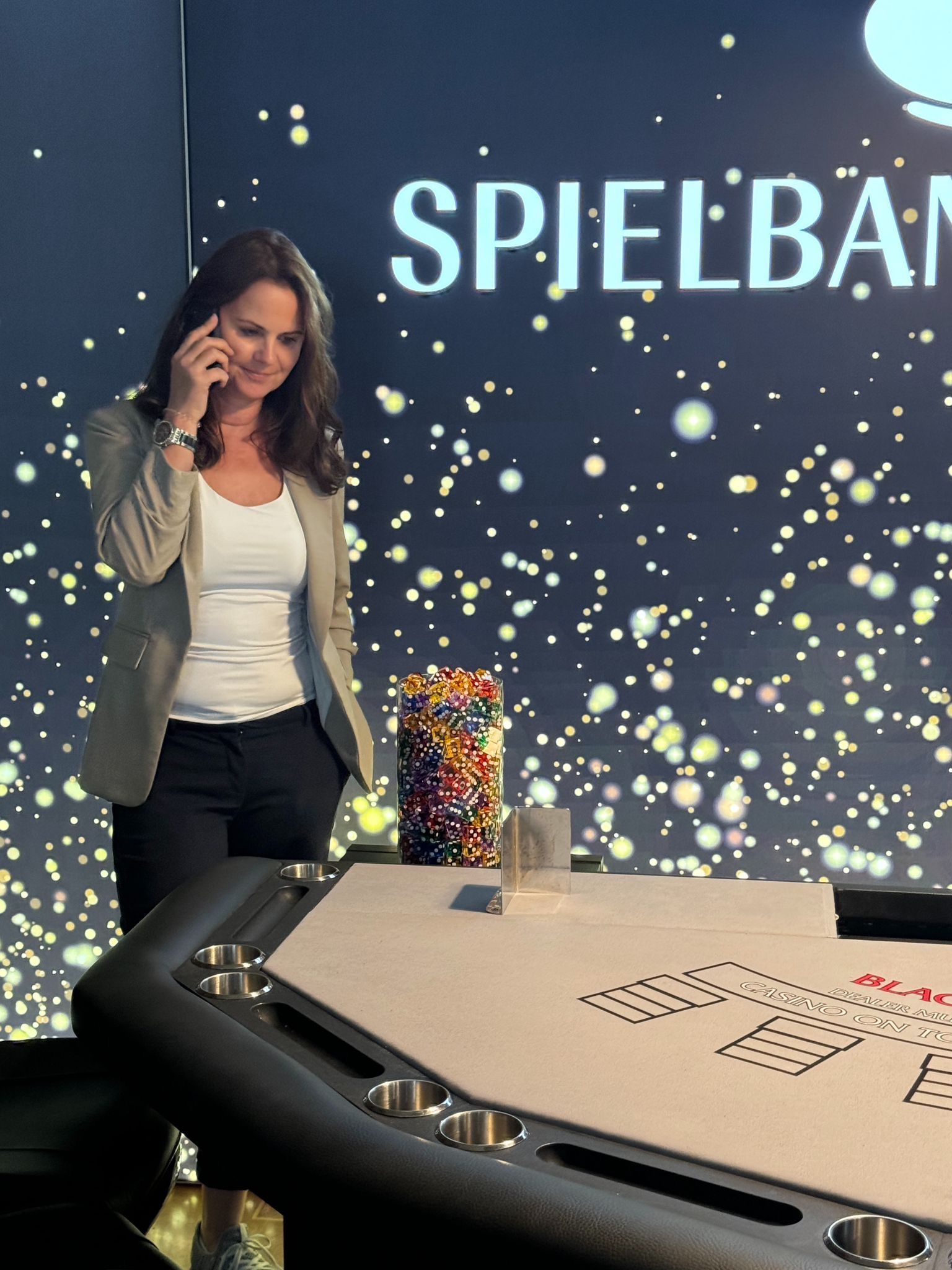 Eine Frau telefoniert mit einem Mobiltelefon vor einem Schild mit der Aufschrift „Spielba“