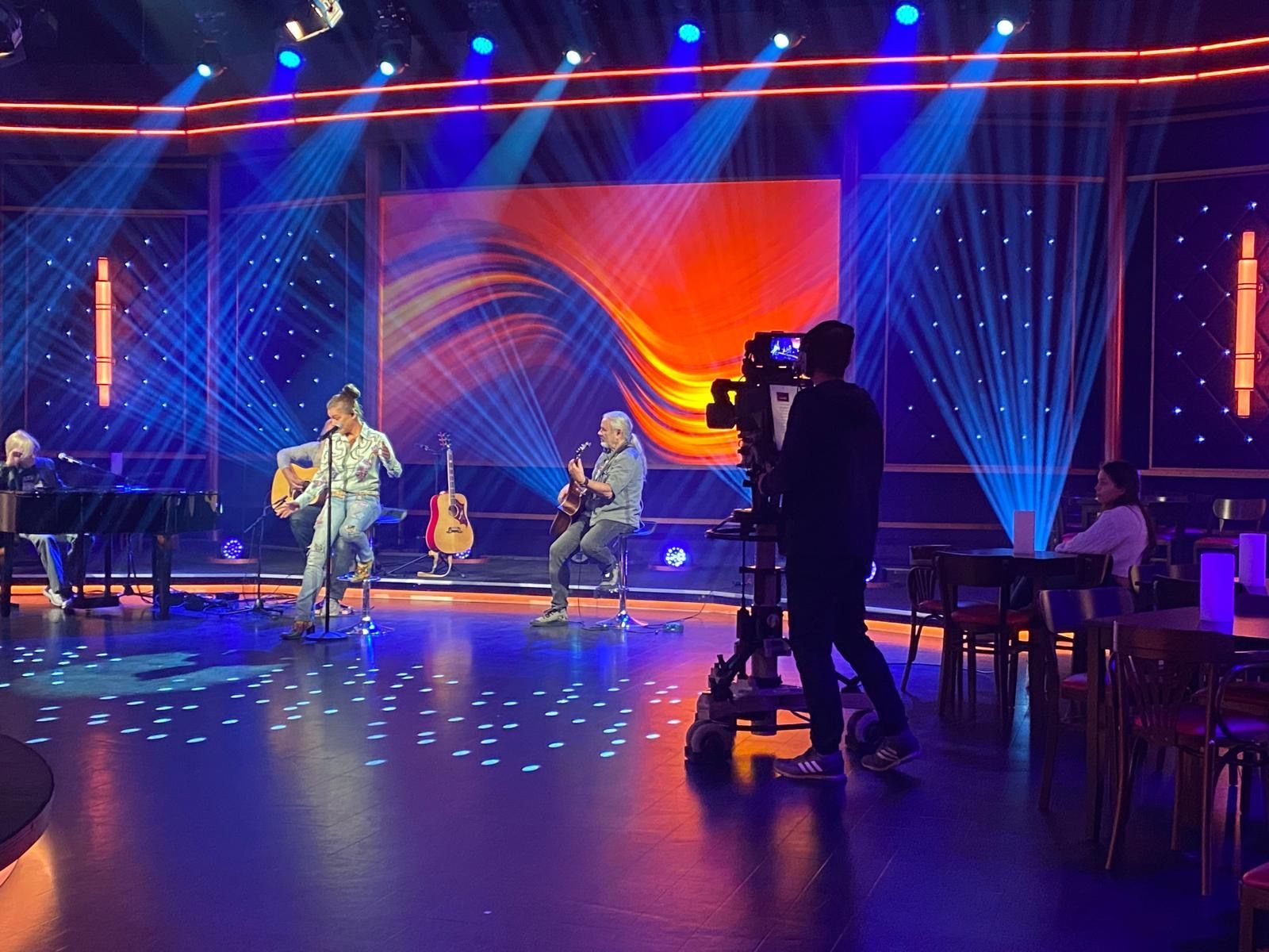 Eine Gruppe von Menschen, die auf einer Bühne Gitarre spielen und singen