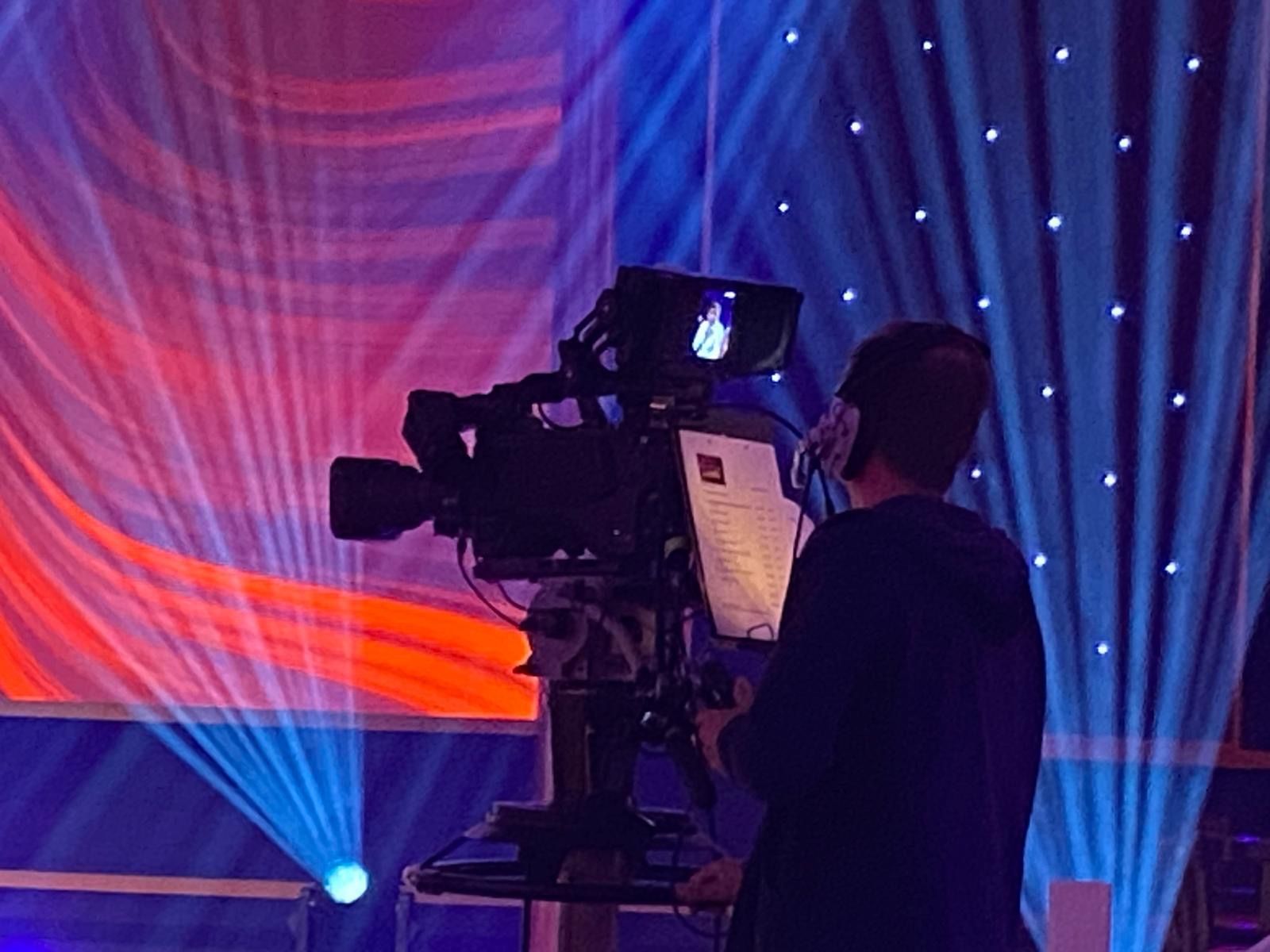 Ein Mann hält eine Kamera vor einer Bühne