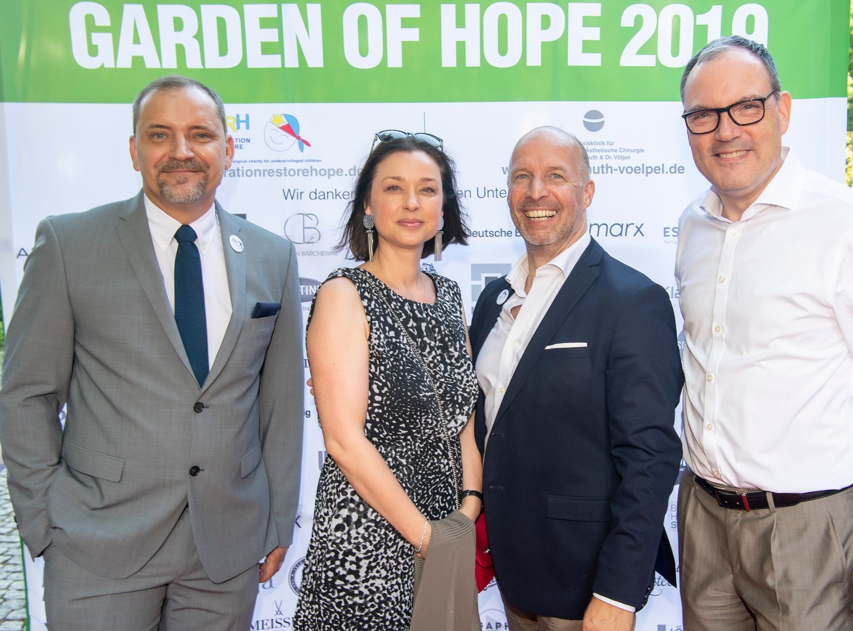 Eine Gruppe von Menschen steht vor einem Schild mit der Aufschrift „Garten der Hoffnung 2019“