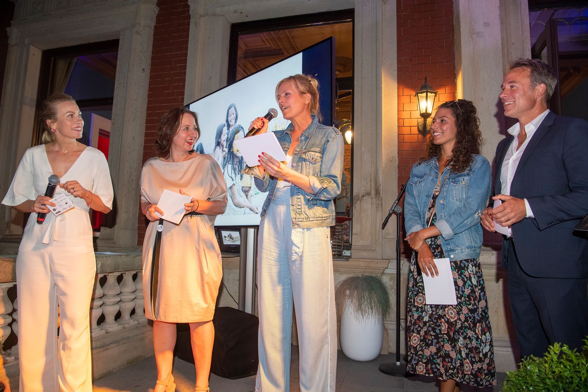 Eine Gruppe von Menschen steht um eine Frau herum, die ein Mikrofon hält