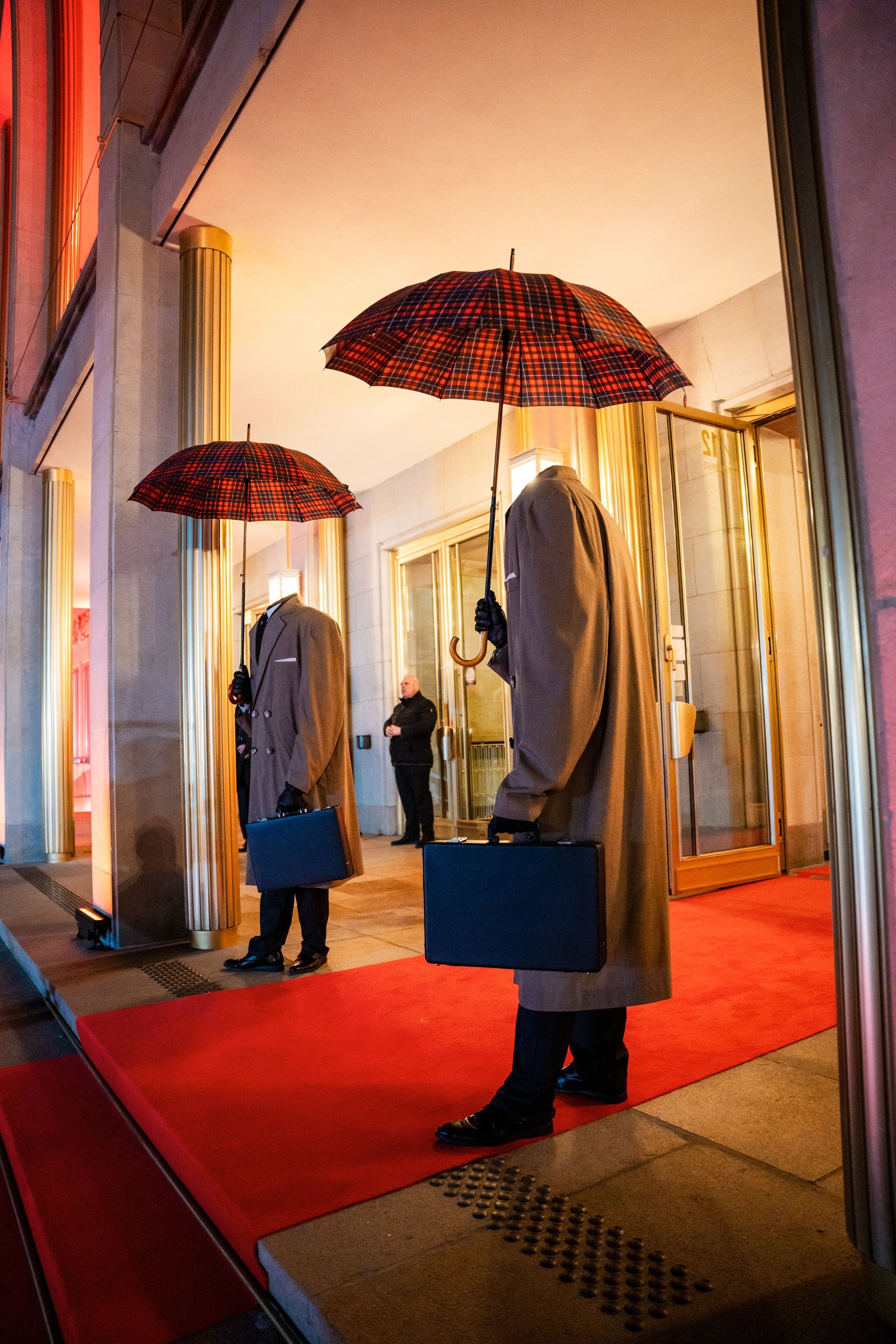 Ein Mann, der auf einem roten Teppich steht und einen Regenschirm hält