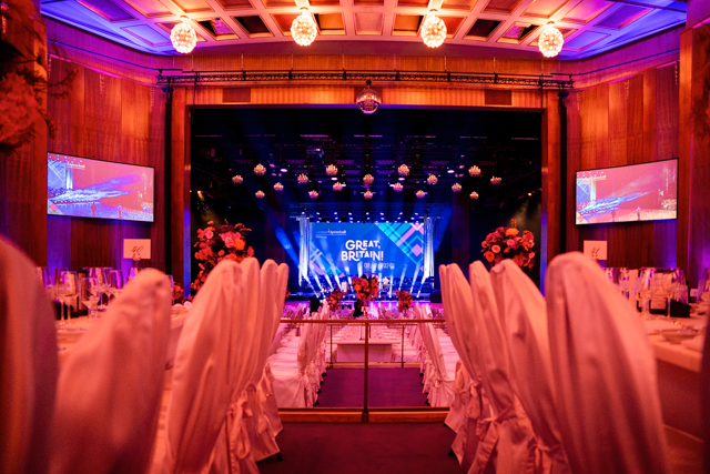 Ein großer Raum mit Tischen und Stühlen und einer Bühne mit einem Schild mit der Aufschrift „Dinner and Dance“ darauf