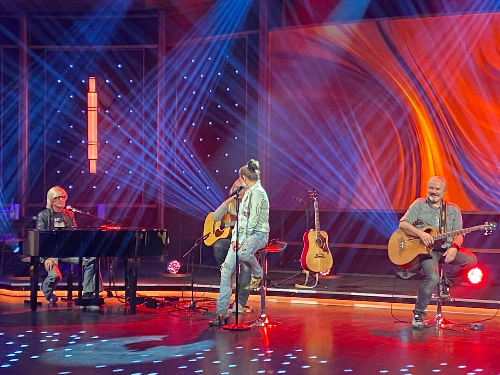 Eine Gruppe von Menschen, die auf einer Bühne Gitarre spielen und singen