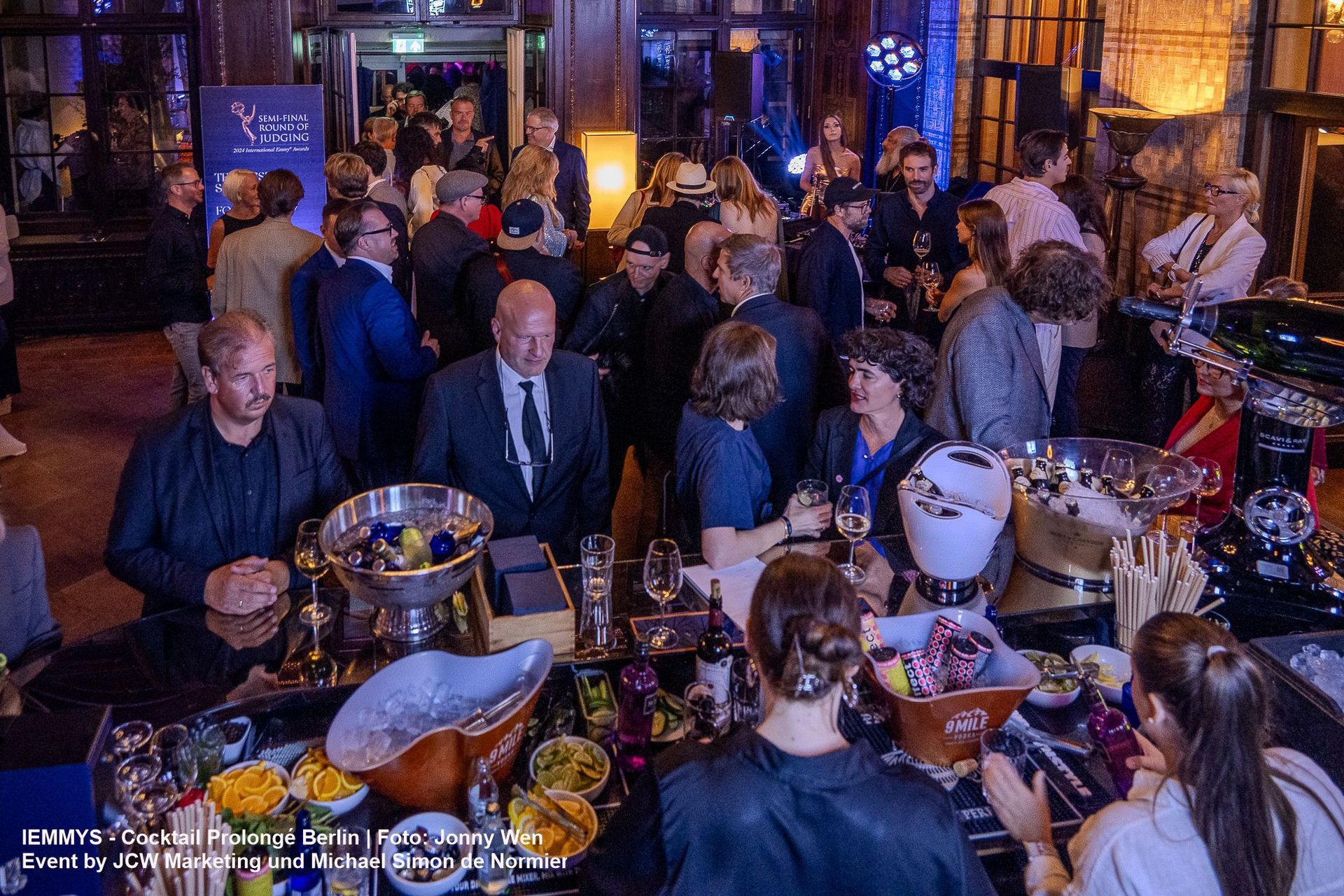 Eine große Gruppe von Menschen ist in einem Raum versammelt, auf dem ein Schild mit der Aufschrift „a“ steht