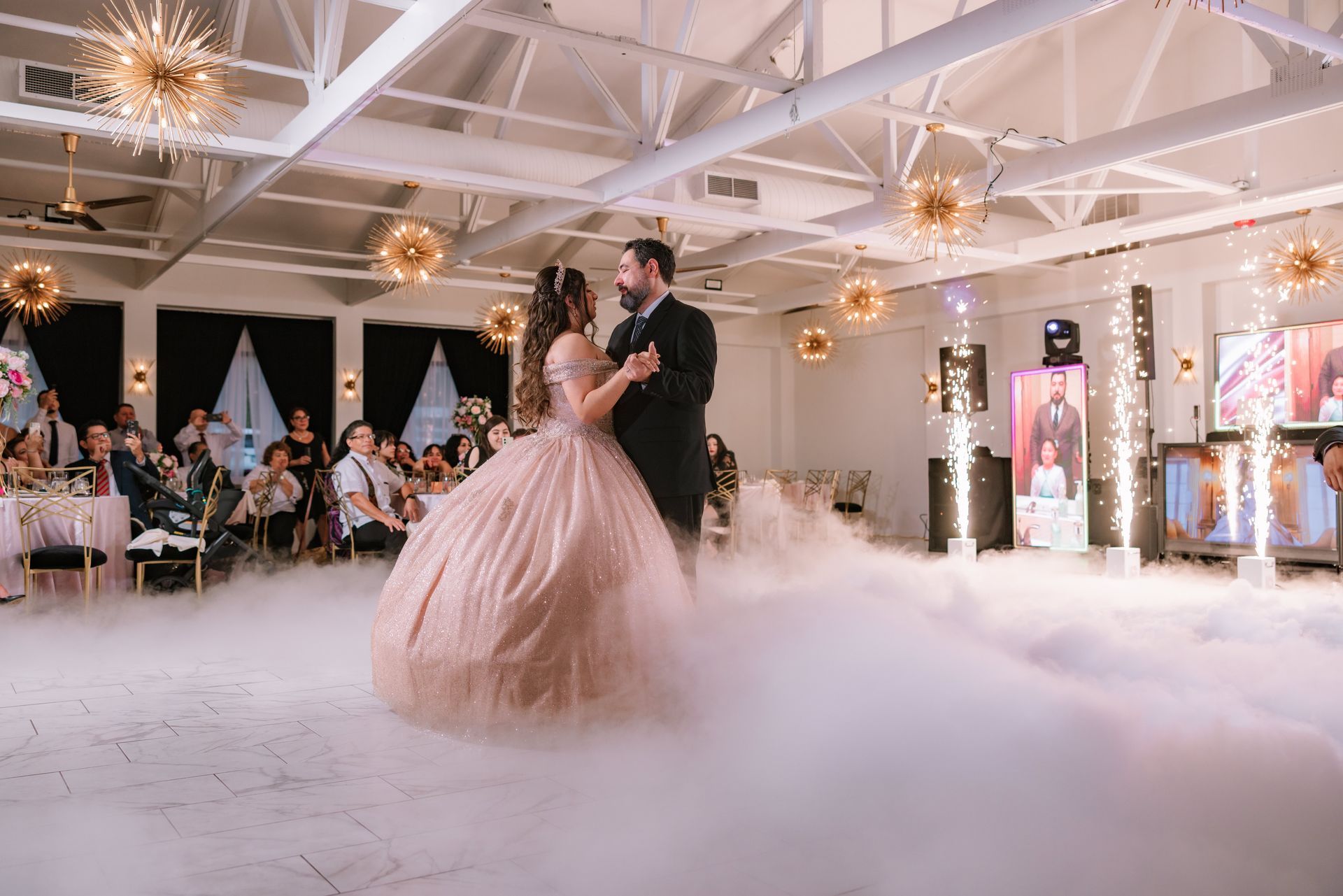 A person in a voluminous royal blue ball gown stands on a wooden bridge, hands on hips, smiling toward the camera.