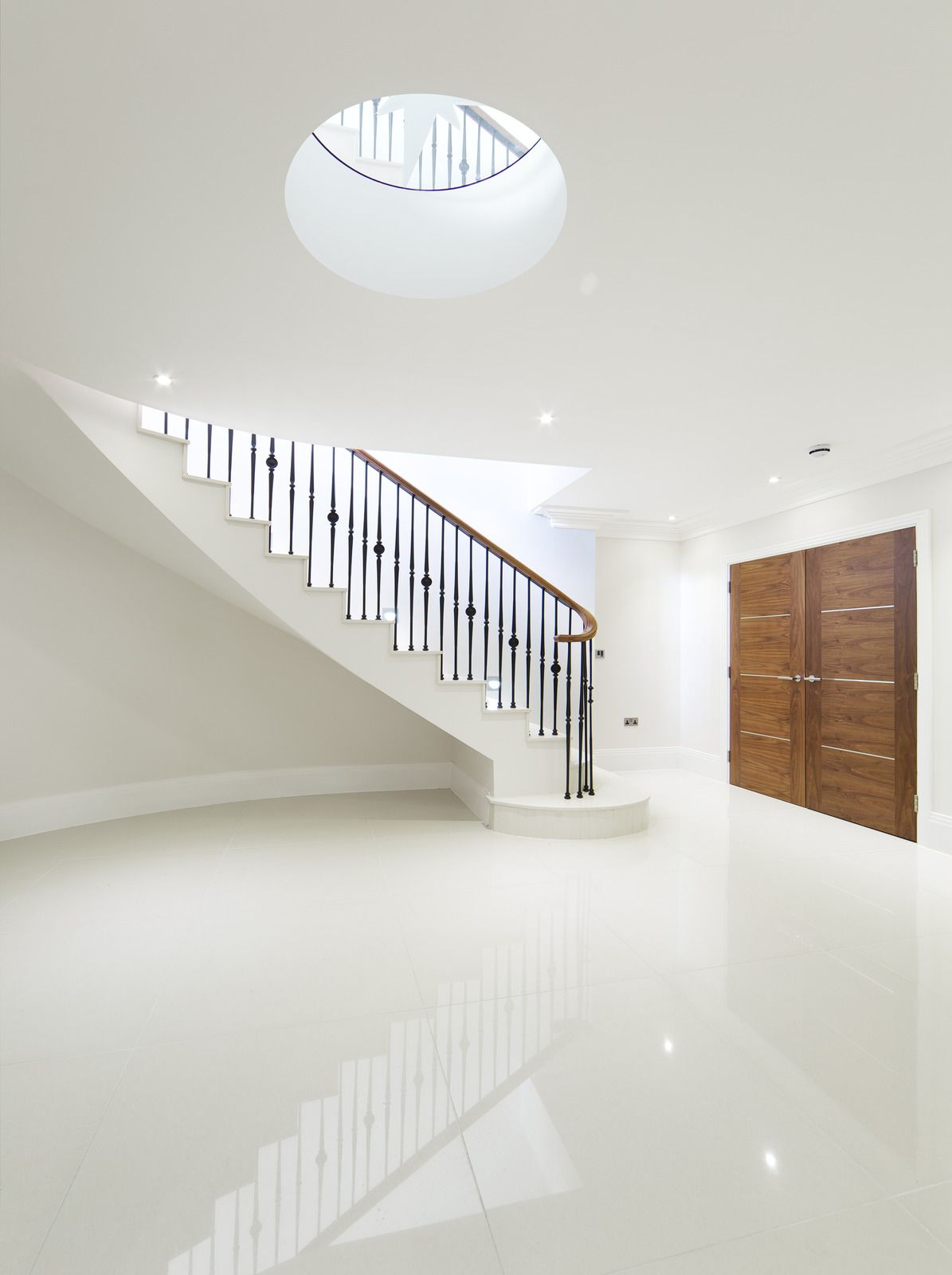 An empty hallway with a staircase and a skylight