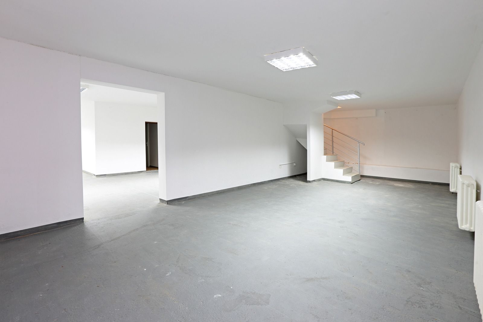 A large empty room with white walls and a staircase.