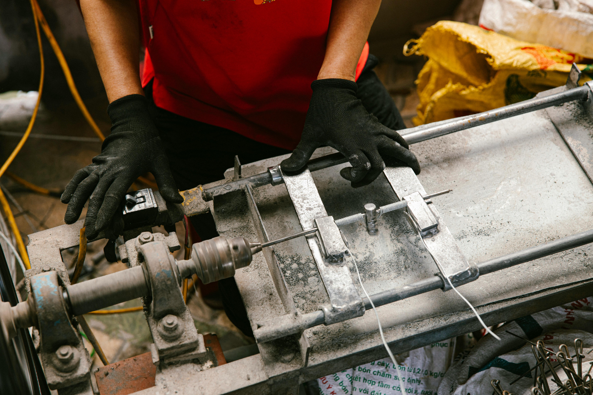 Person operating machinery with black gloves; red shirt.