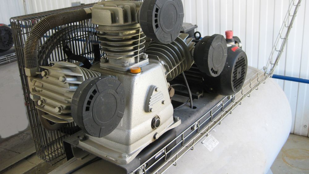 Air compressor with metal components and a cylindrical tank.