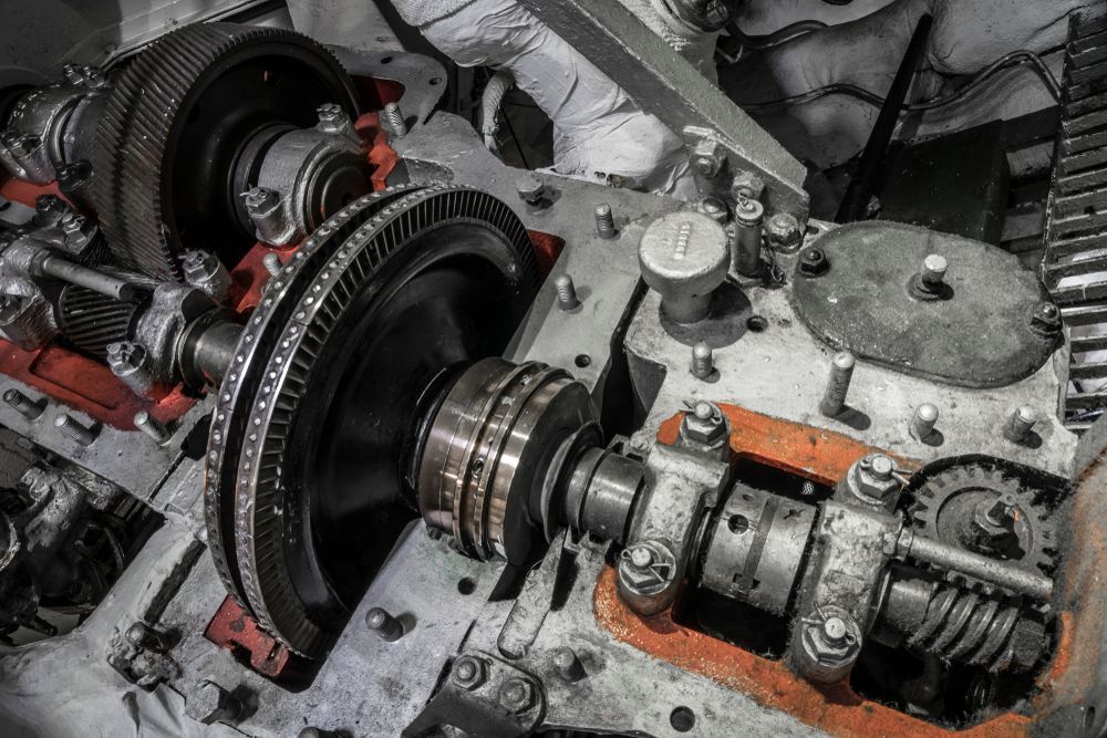 Close-up of industrial machinery, gears, bearings, and mechanical components. Metal construction, orange accenting.
