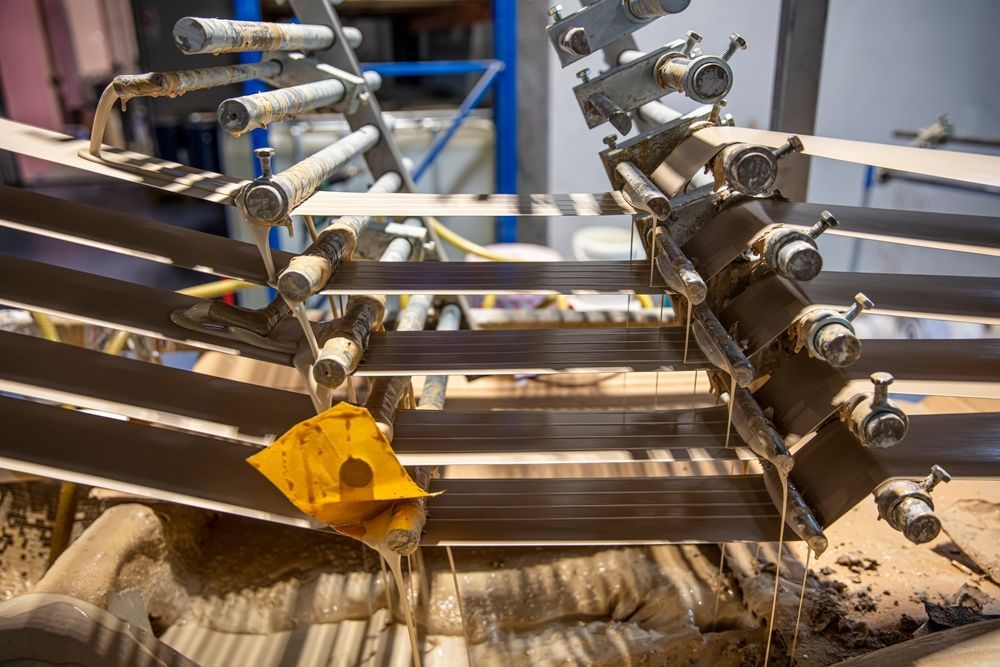 Industrial machinery with metal rollers and a single leaf caught in the process.