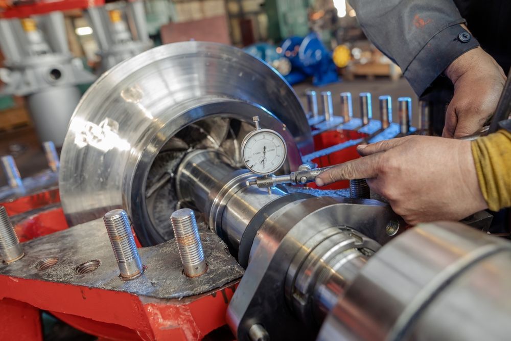 Person using a dial indicator to measure the rotor of a large industrial pump.