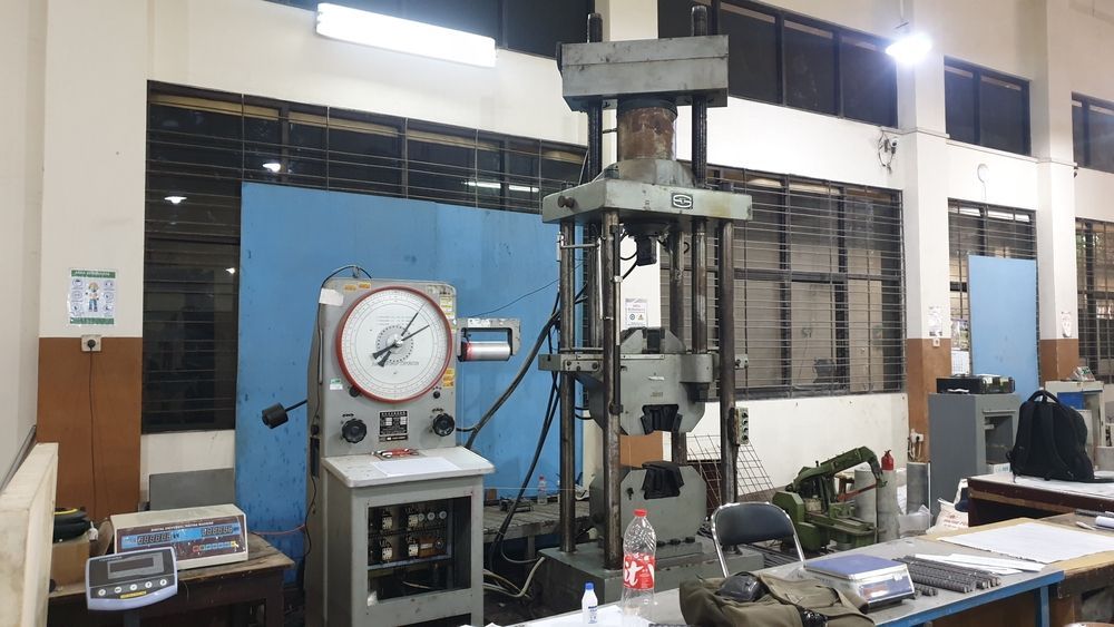 Testing machine in a lab setting, featuring a large pressure gauge and control panel.