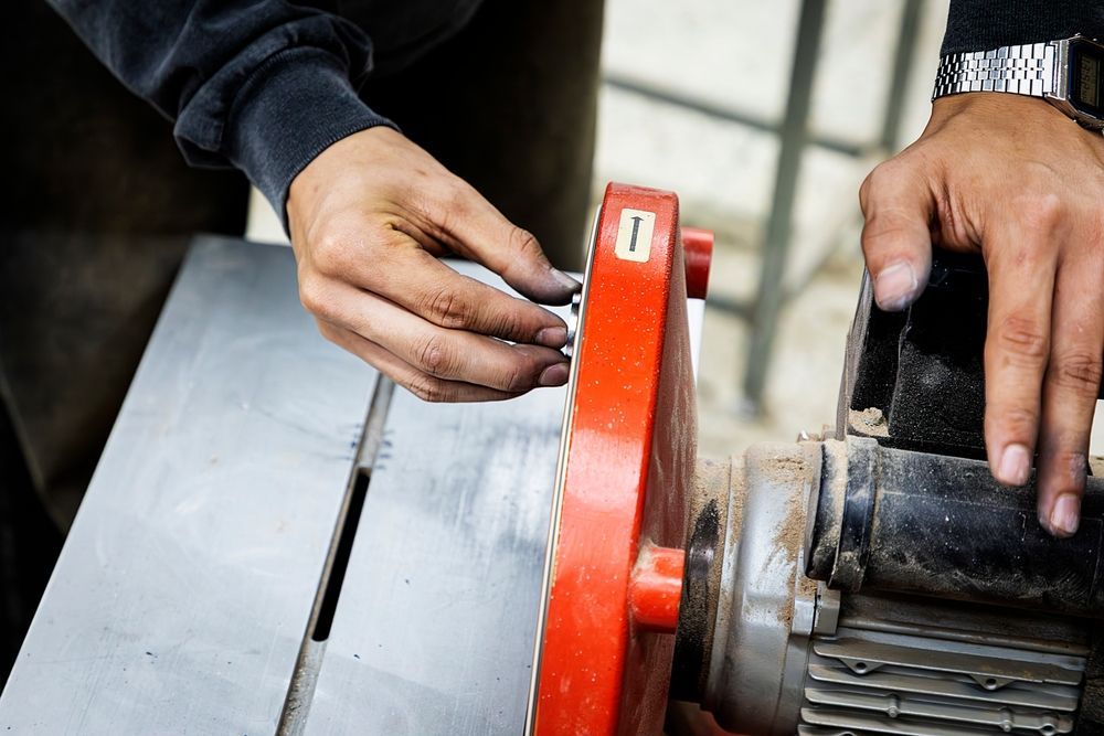Hands adjusting a red saw blade guard on a table saw.