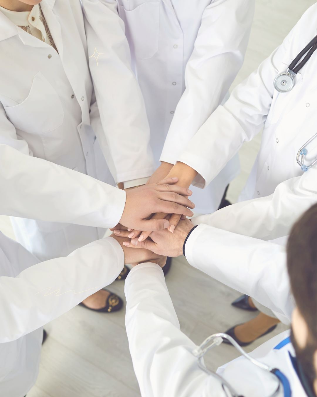 Um grupo de médicos juntando as mãos em círculo