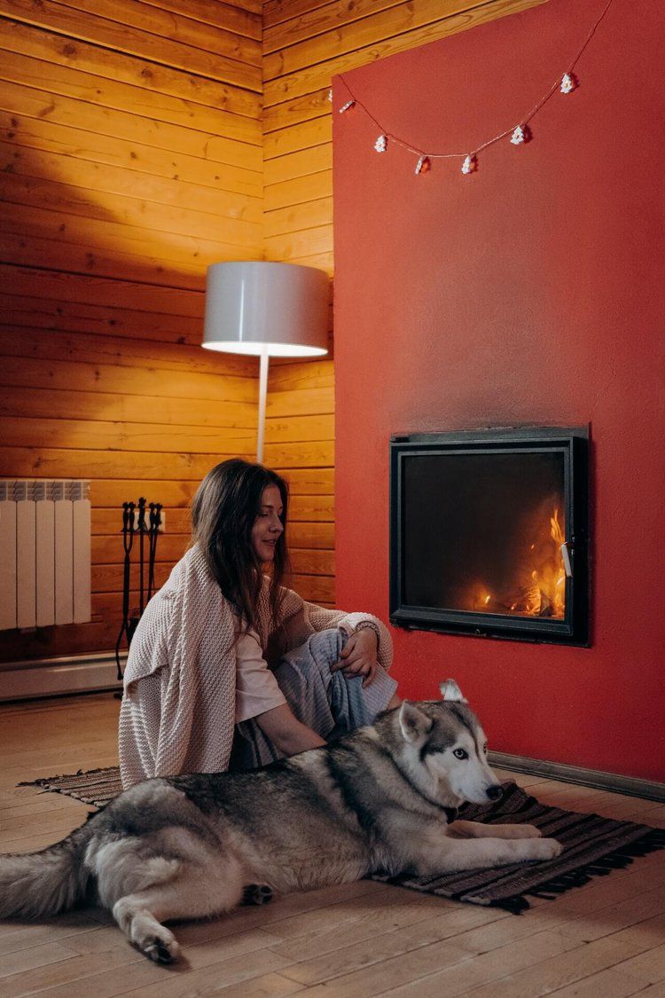 girl with her dog sitting near a fireplace