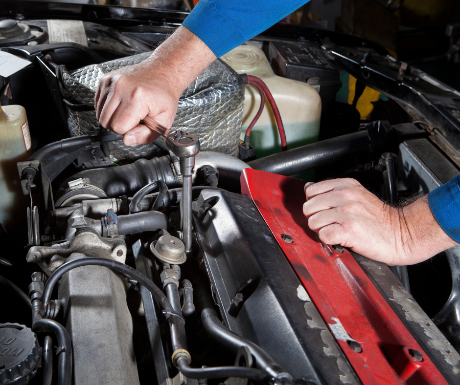 Mechanic working on an engine with a wrench, focusing on the mechanical components.